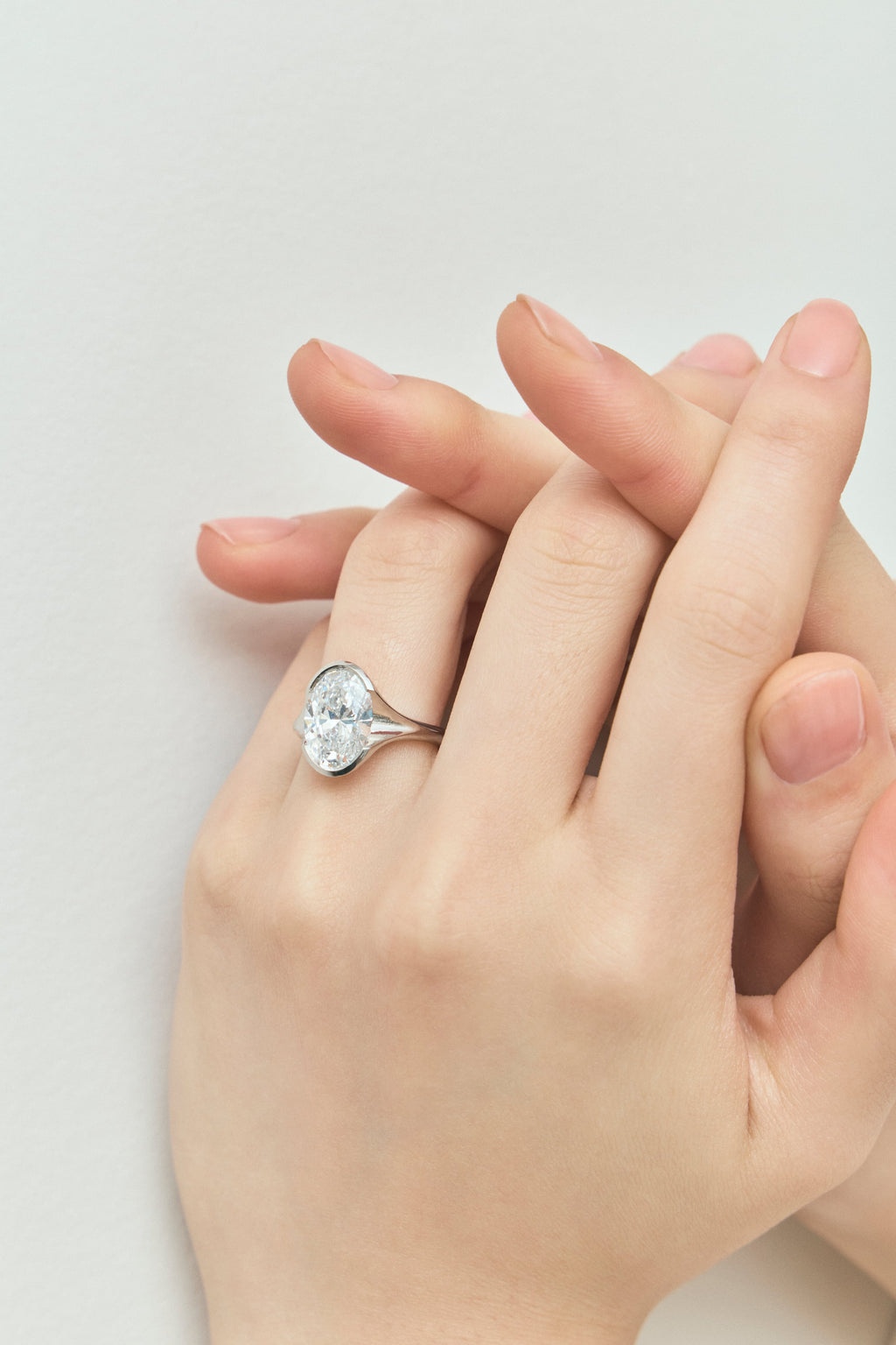 Model wears Bond 4ct oval solitaire semi-bezel engagement ring in 18ct white gold