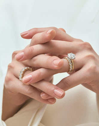 Model wears Cambon round brilliant six claw solitaire swept shoulder engagement ring in 18ct yellow gold