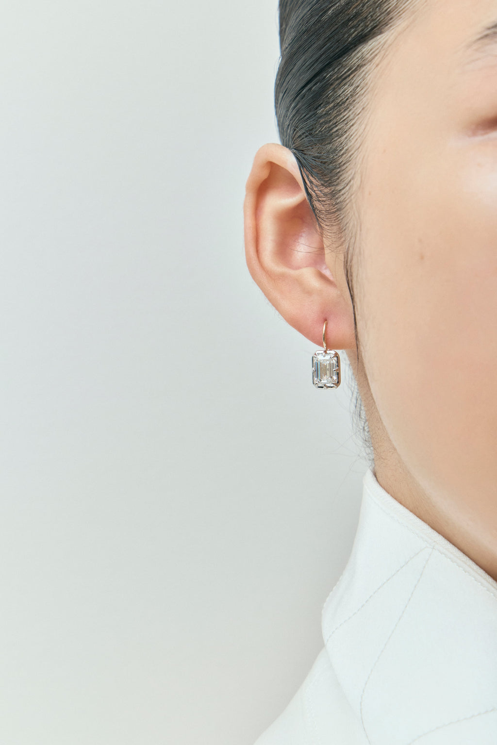 Model wears Avalon 2ct emerald cut button drop earrings in 18ct yellow gold