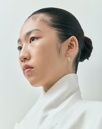 Model wears Avalon 2ct emerald cut button drop earrings in 18ct yellow gold