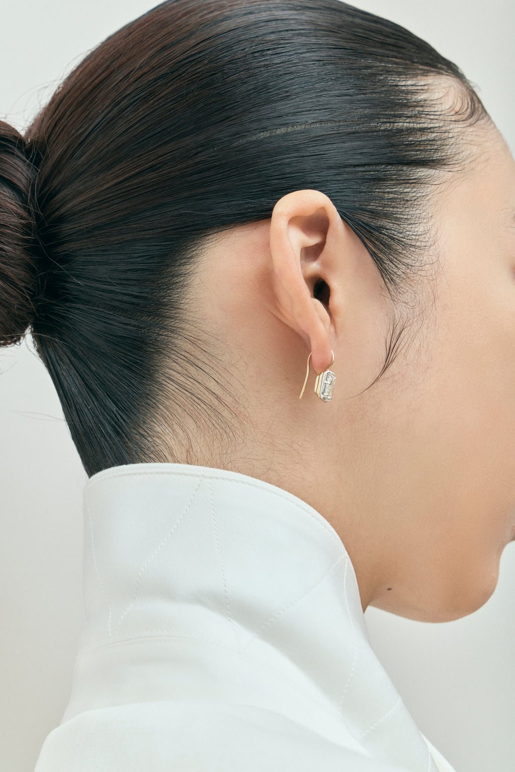 Model wears Avalon 2ct emerald cut button drop earrings in 18ct yellow gold