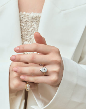 Model wears Vestry 3ct pear solitaire scalloped engagement ring in 18ct yellow gold