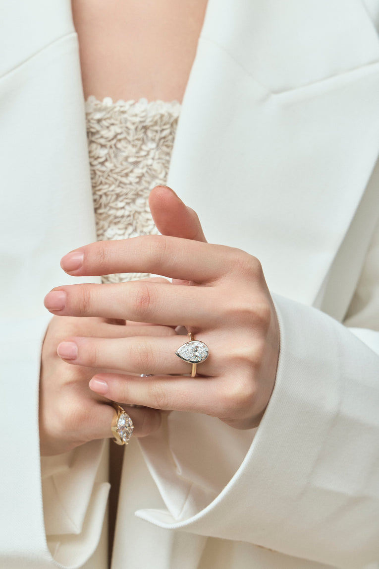 Model wears Vestry 3ct pear solitaire scalloped engagement ring in 18ct yellow gold