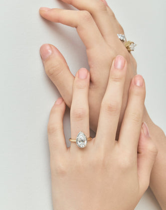 Model wears Vestry 3ct pear solitaire scalloped engagement ring in 18ct yellow gold
