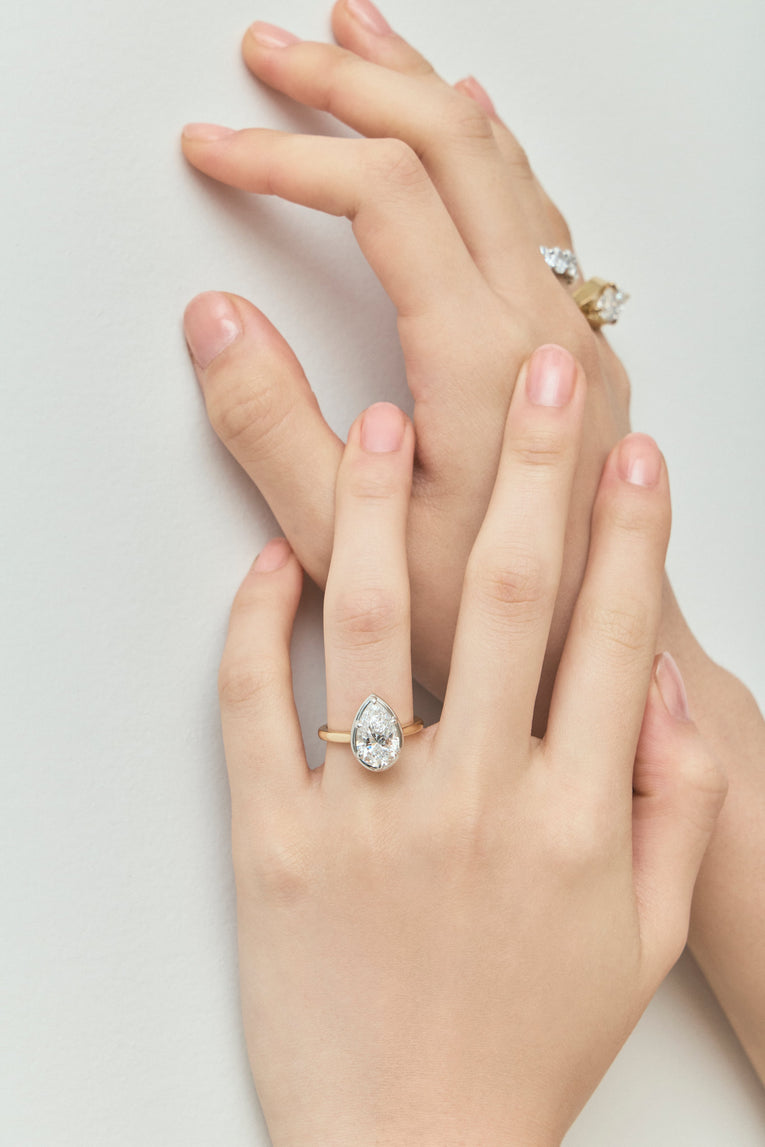 Model wears Vestry 3ct pear solitaire scalloped engagement ring in 18ct yellow gold