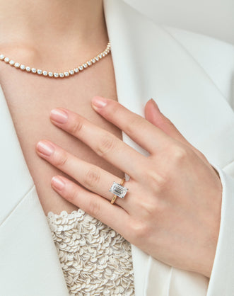 Model wears Dover emerald cut solitaire swept shoulder engagement ring in 18ct yellow gold