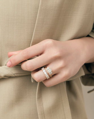 Model wears Marion emerald cut trilogy engagement ring in 18ct yellow gold