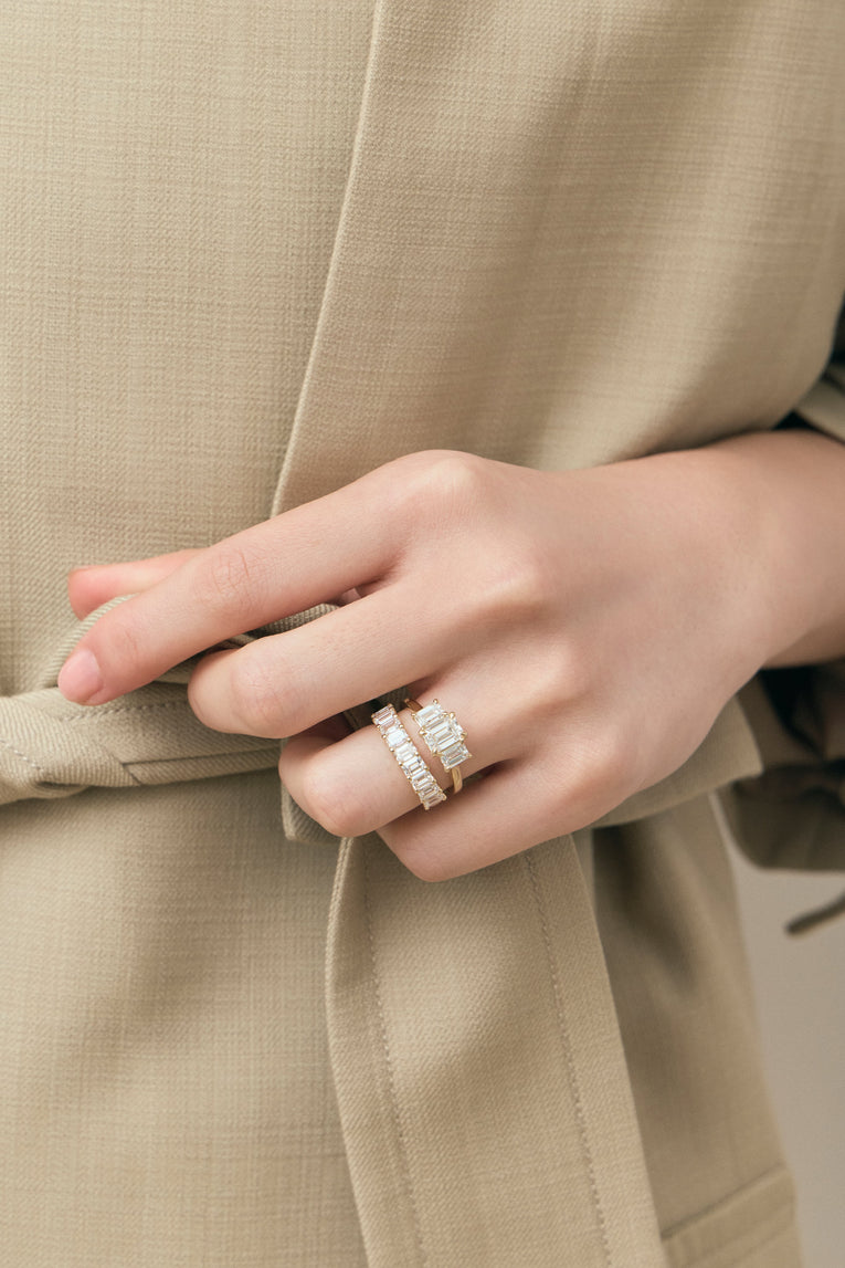 Model wears Marion emerald cut trilogy engagement ring in 18ct yellow gold