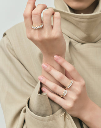 Model wears Marion emerald cut trilogy engagement ring in 18ct yellow gold