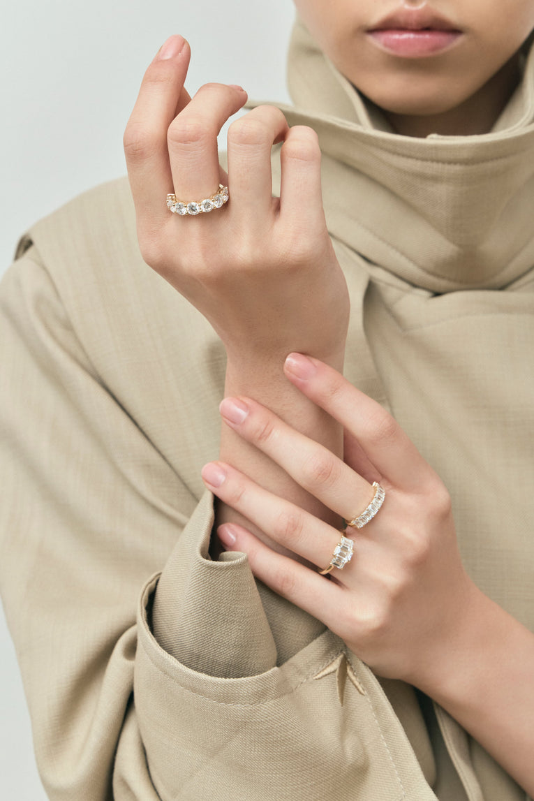 Model wears Marion emerald cut trilogy engagement ring in 18ct yellow gold