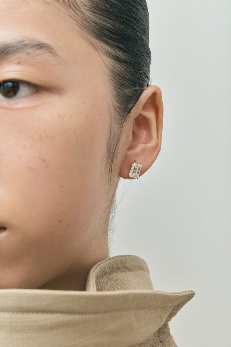 Model wears Clark 2ct emerald cut diamond studs in 18ct yellow gold