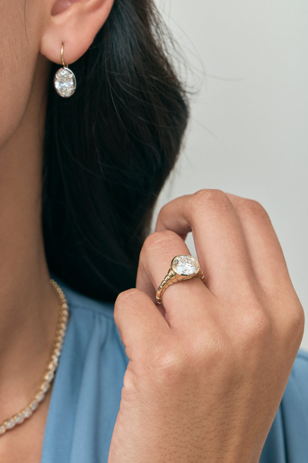 Model wears Chrystie 3ct round brilliant signet bezel grooved band engagement ring in 18ct yellow gold