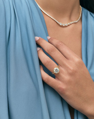 Model wears Chrystie 3ct round brilliant signet bezel grooved band engagement ring in 18ct yellow gold