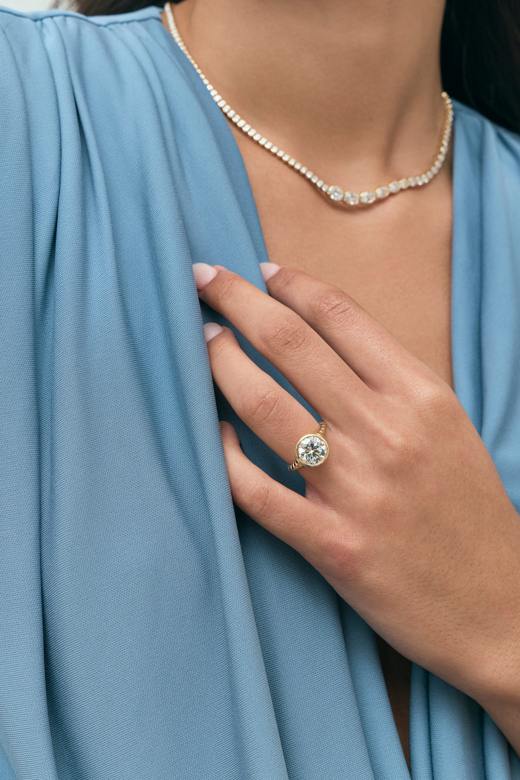 Model wears Chrystie 3ct round brilliant signet bezel grooved band engagement ring in 18ct yellow gold