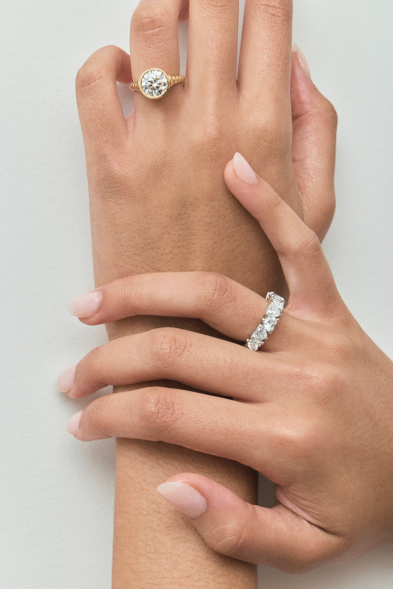 Model wears Chrystie 3ct round brilliant signet bezel grooved band engagement ring in 18ct yellow gold