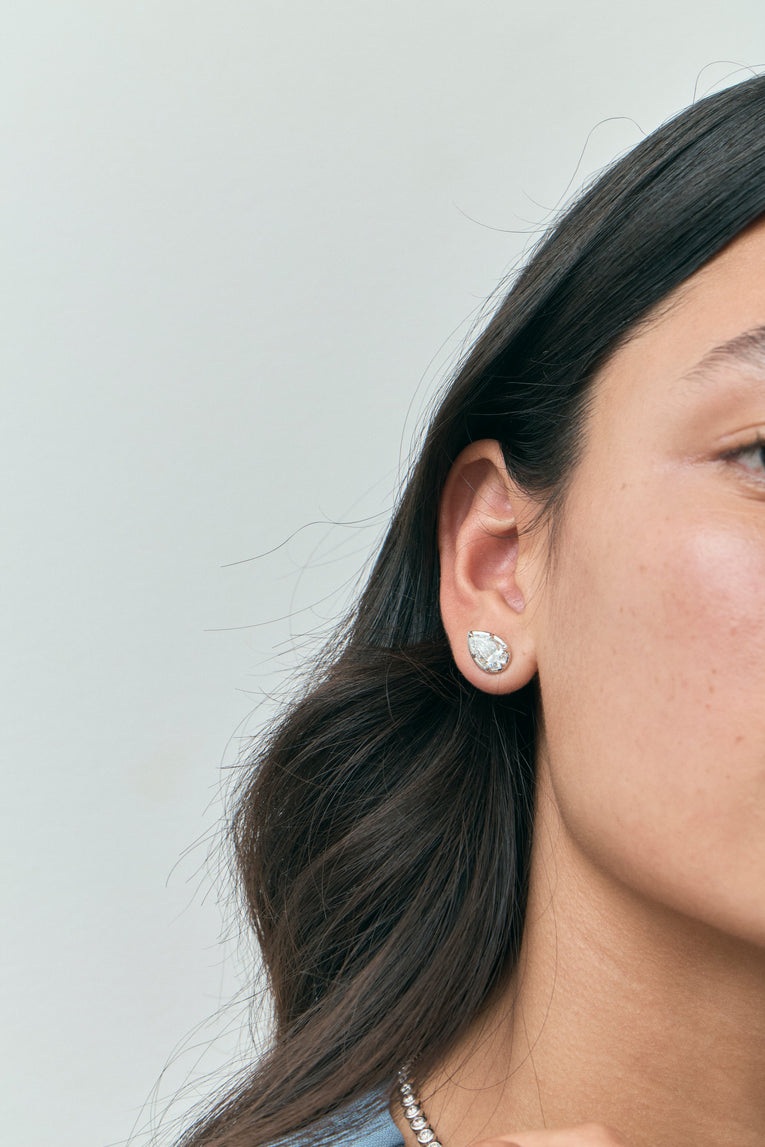 Model wears Moncur 1.5ct pear cut diamond studs in 18ct white gold