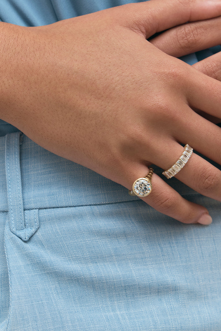 Close-up model wears Soho 0.30ct emerald cut half eternity band in 18ct yellow gold