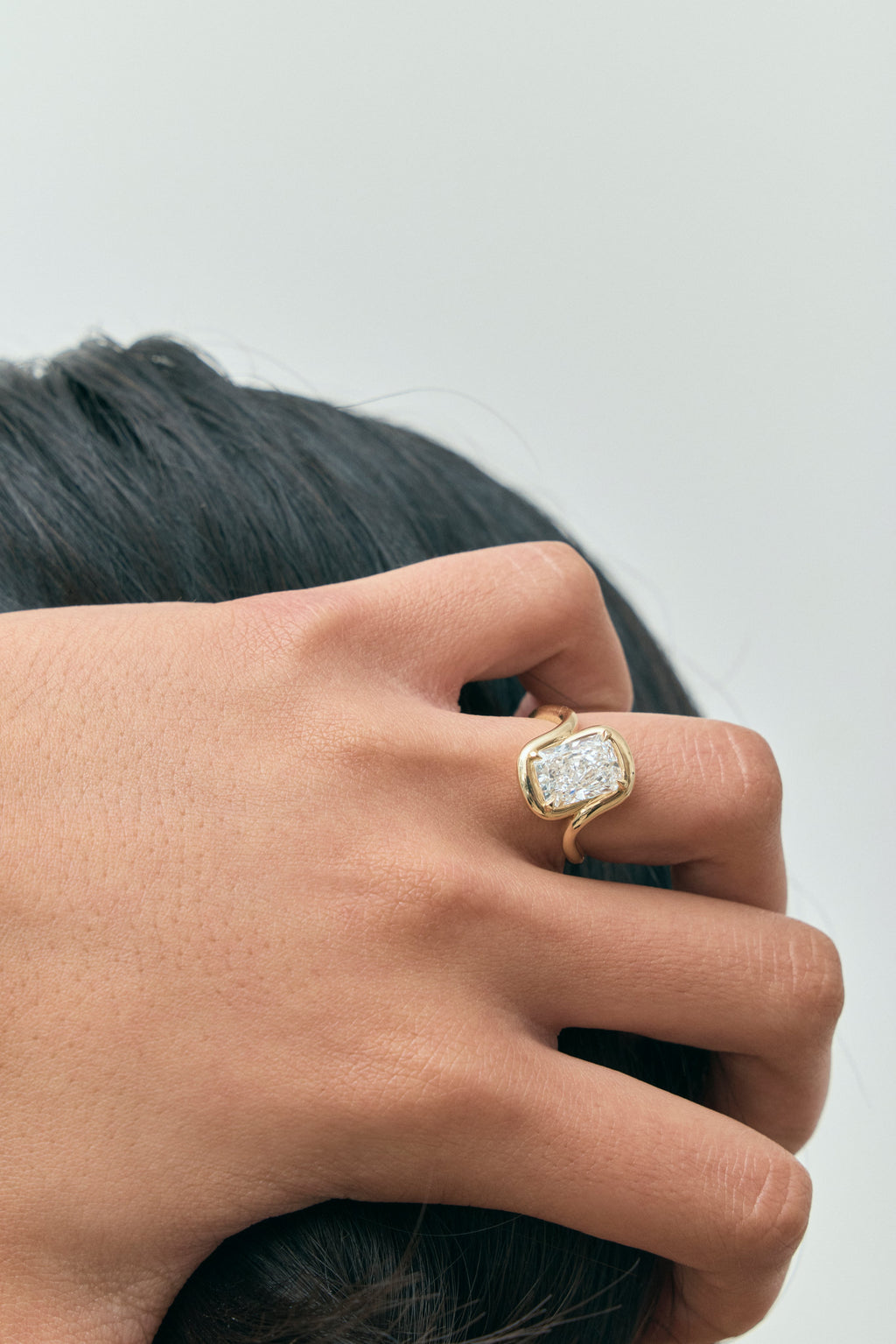 Model wears Prince 3ct radiant cut curved band engagement ring in 18ct yellow gold