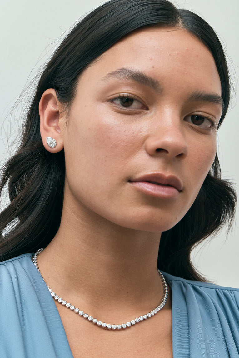 Model wears Moncur 1.5ct pear cut diamond studs in 18ct white gold