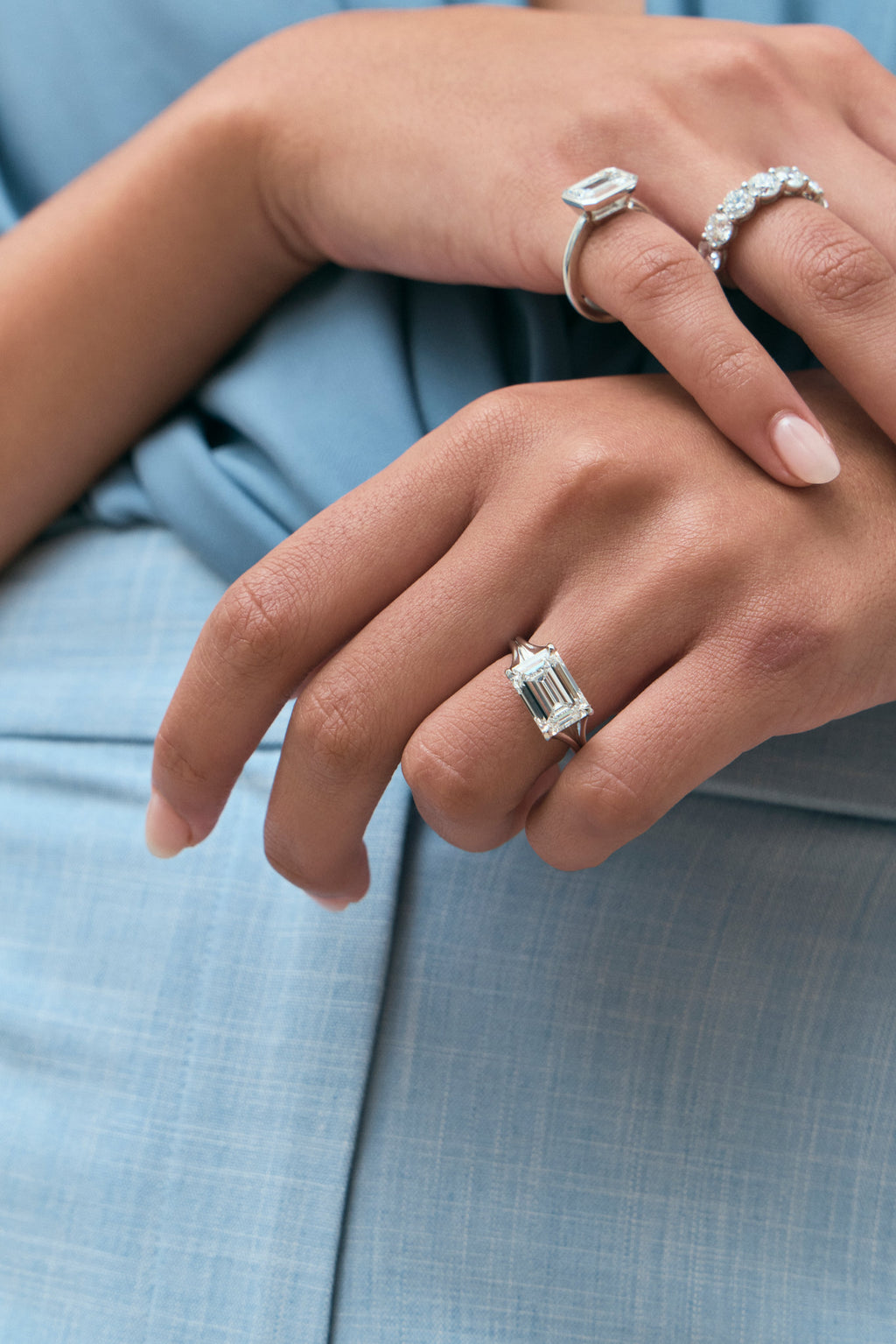Model wears Perry East-West 5ct emerald solitaire double band engagement ring in 18ct white gold