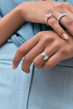 Model wears Perry East-West 5ct emerald solitaire double band engagement ring in 18ct white gold
