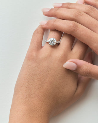 Model wears Hudson 4ct round brilliant tapered baguette engagement ring in 18ct white gold