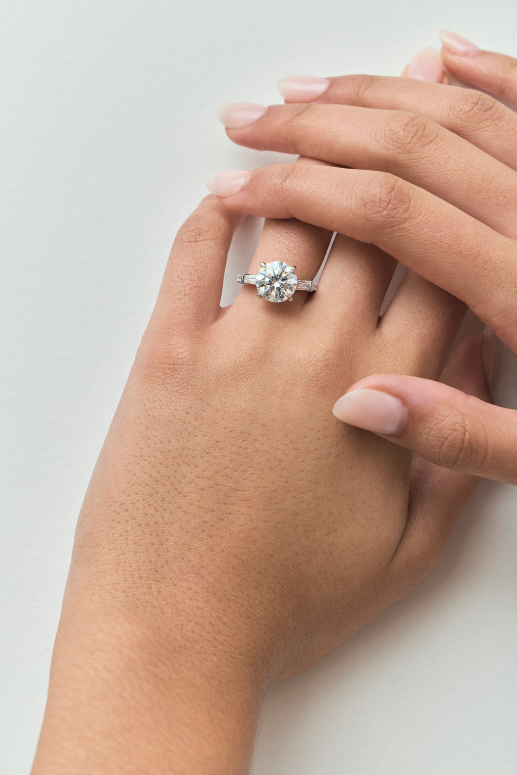 Model wears Hudson 4ct round brilliant tapered baguette engagement ring in 18ct white gold