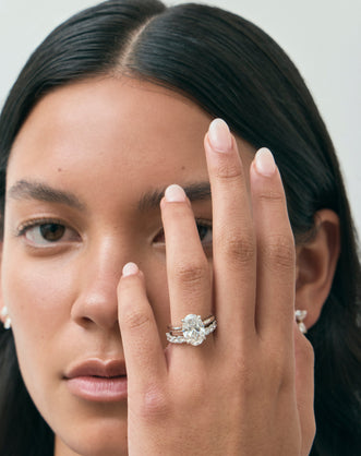 Model wears Montaigne oval solitaire swept shoulder engagement ring in 18ct white gold