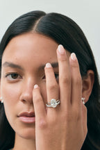 Model wears Montaigne oval solitaire swept shoulder engagement ring in 18ct white gold