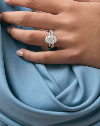 Model wears Montaigne oval solitaire swept shoulder engagement ring in 18ct white gold