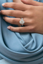 Model wears Montaigne oval solitaire swept shoulder engagement ring in 18ct white gold