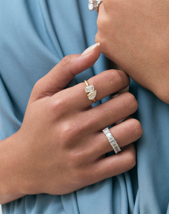 Close-up model wears Kinney Toi Et Moi pear emerald engagement ring in 18ct yellow gold