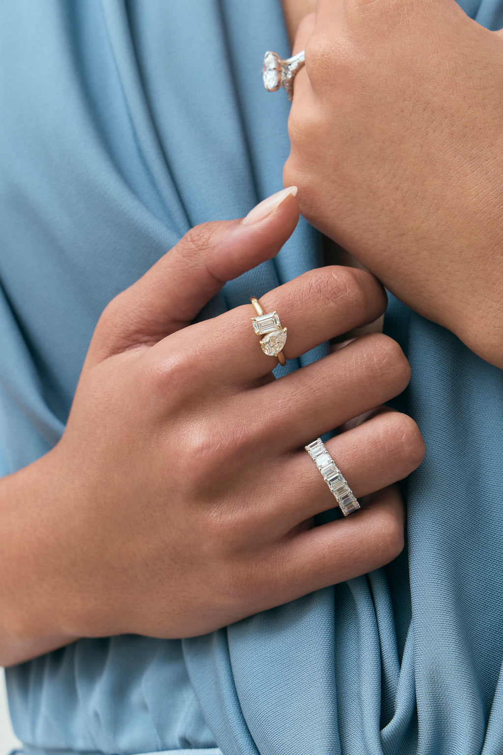 Close-up model wears Kinney Toi Et Moi pear emerald engagement ring in 18ct yellow gold