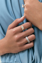 Close-up model wears Kinney Toi Et Moi pear emerald engagement ring in 18ct yellow gold