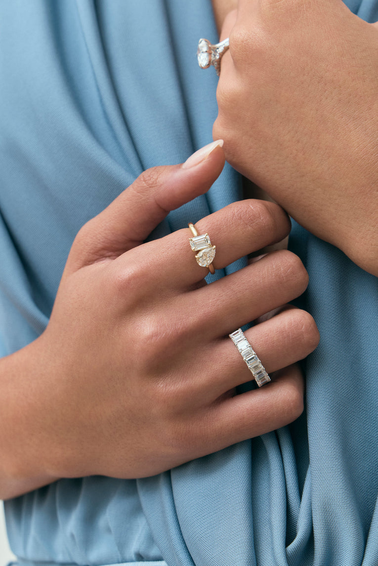 Close-up model wears Kinney Toi Et Moi pear emerald engagement ring in 18ct yellow gold