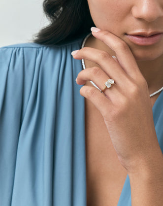 Close-up model wears Kinney Toi Et Moi pear emerald engagement ring in 18ct yellow gold