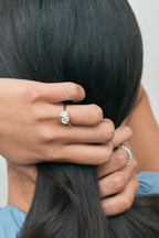 Close-up model wears Kinney Toi Et Moi pear emerald engagement ring in 18ct yellow gold