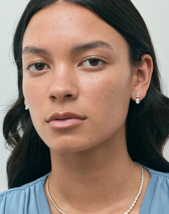 Model wears Madame 0.50ct emerald pear cut drop earrings in 18ct white gold