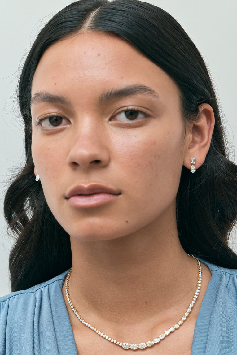 Model wears Madame 0.50ct emerald pear cut drop earrings in 18ct white gold