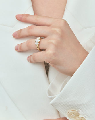 Model wears Clarkson oval trilogy engagement ring in 18ct yellow gold