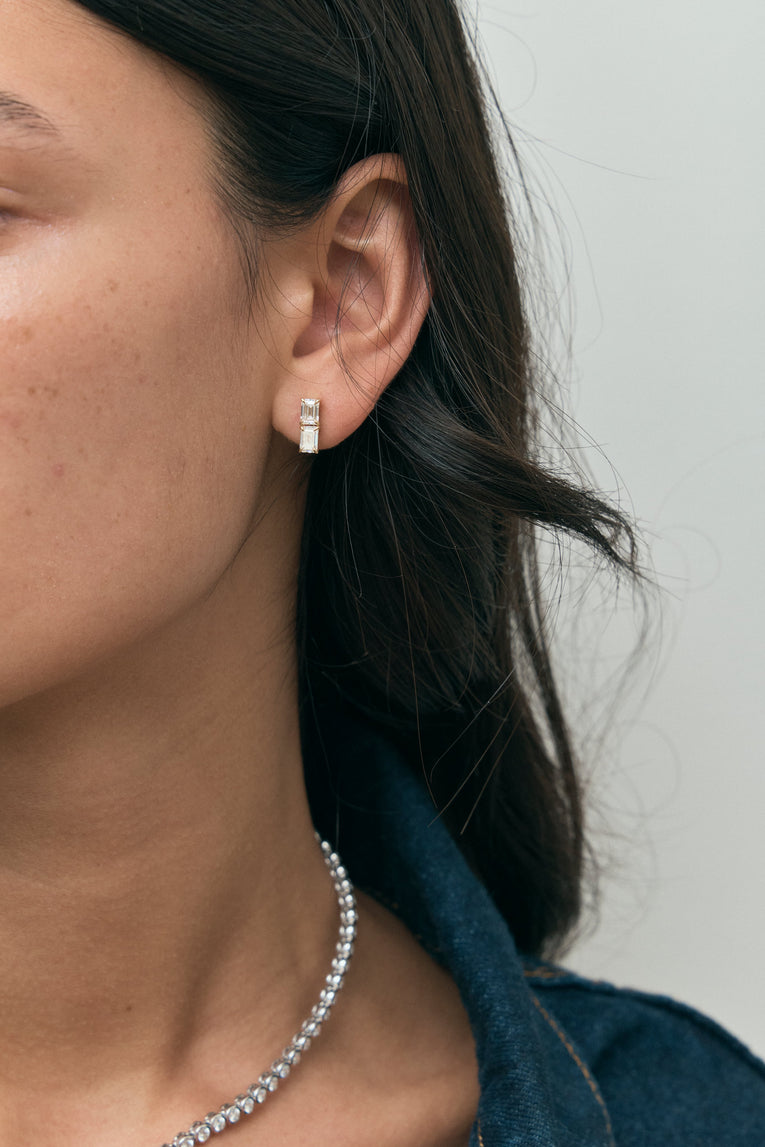 Model wears Charlot double 0.50ct emerald cut drop earrings in 18ct yellow gold