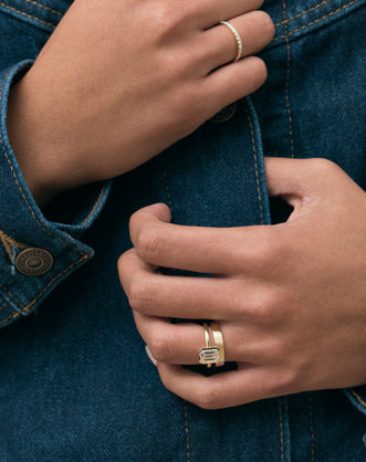 Model wears Sutton emerald cut solitaire bezel north-south engagement ring in 18ct yellow gold