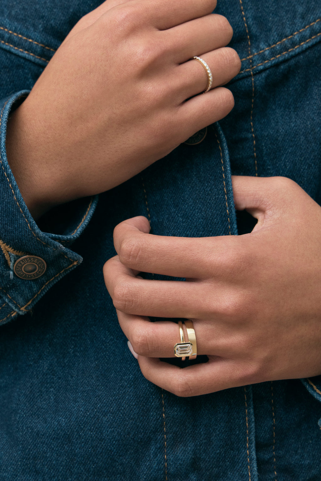 Model wears Sutton emerald cut solitaire bezel north-south engagement ring in 18ct yellow gold