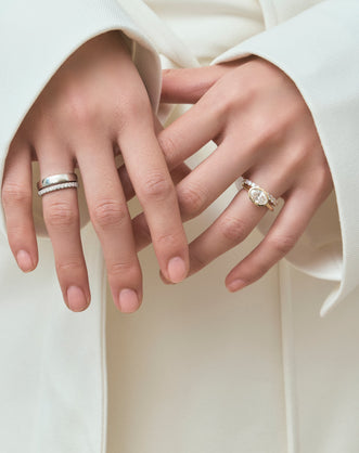 Model wears Maddox oval solitaire bezel east-west engagement ring in 18ct yellow gold