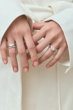 Model wears Maddox oval solitaire bezel east-west engagement ring in 18ct yellow gold