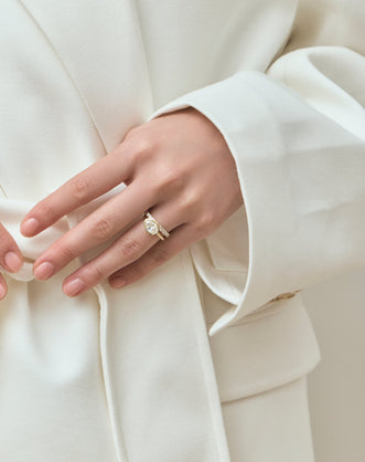 Model wears Maddox oval solitaire bezel east-west engagement ring in 18ct yellow gold