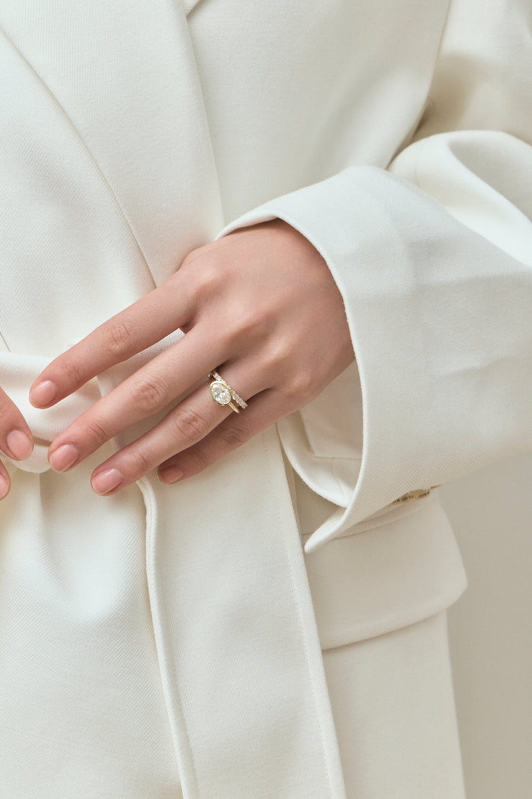 Model wears Maddox oval solitaire bezel east-west engagement ring in 18ct yellow gold