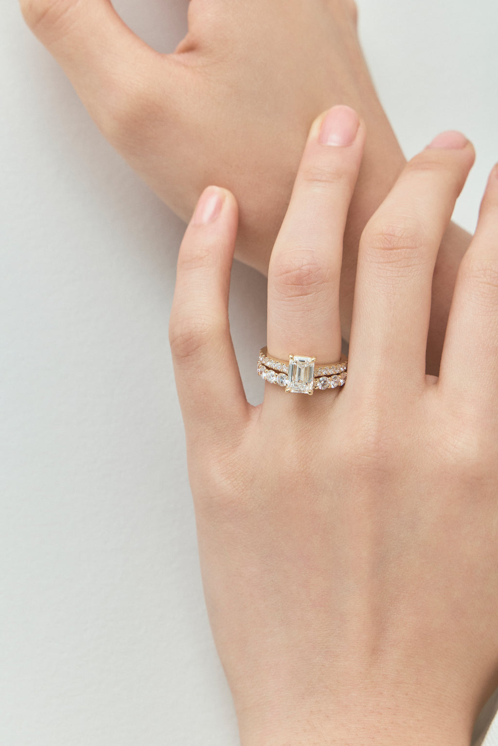 Model wears Beverly emerald cut diamond band engagement ring in 18ct yellow gold 