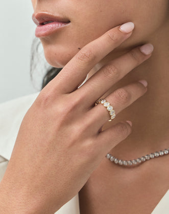 Close-up model wears Tournon 0.20ct oval bezel set half eternity band in 18ct yellow gold