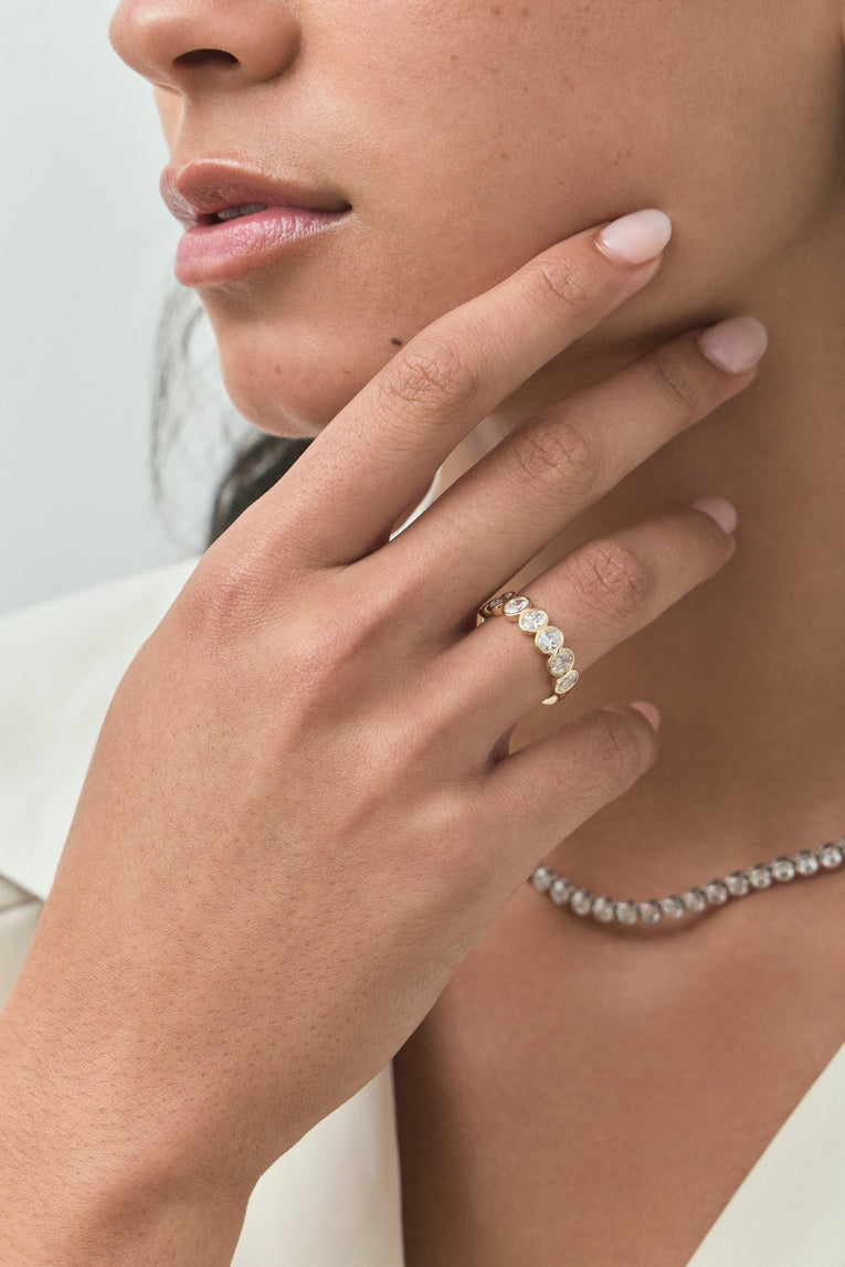 Close-up model wears Tournon 0.20ct oval bezel set half eternity band in 18ct yellow gold